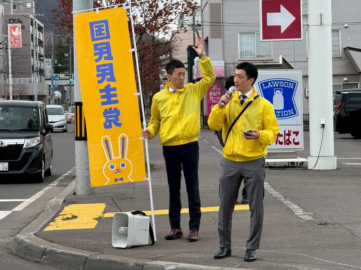 国民民主党ののぼりを持つ仲間と街頭に立つ阿部恭介